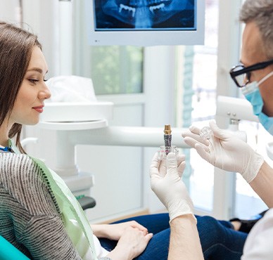 A dentist showing a dental implant to his patient