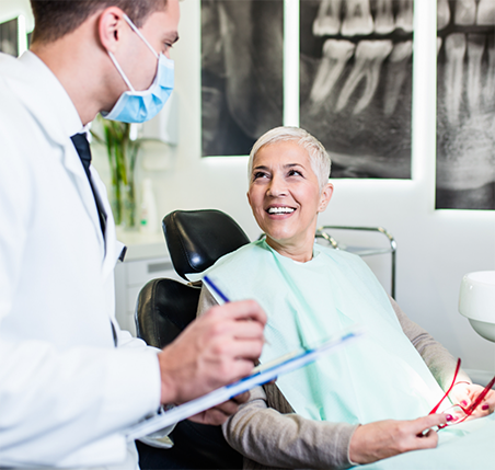 Lady smiling while talking to dentist about the cost of dental implants.